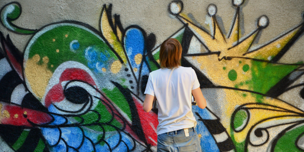 autistic teen paints on a wall in bright colours. Expressing their autistic self.